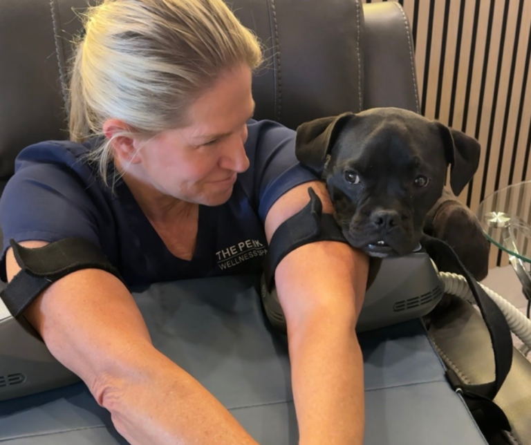 Edye receives an Emsculpt Neo treatment on her arms while Beau, The Peak Wellness Pup, keeps her company at The Peak Wellness Spa in Scottsdale.