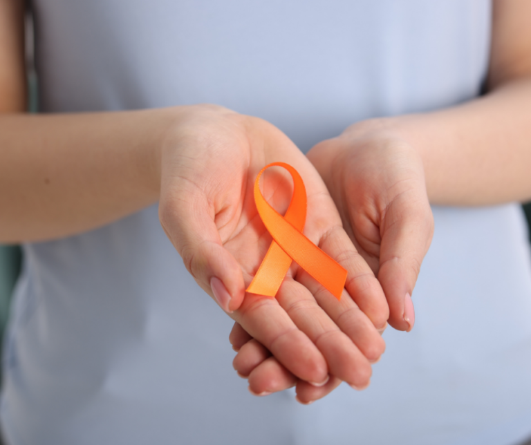Person holding an orange multiple sclerosis awareness ribbon in support of MS wellness and symptom management.